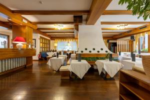 a restaurant with white tables and white chairs at Royal Olympic Hotel in Pinzolo