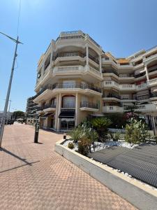 a large white building with balconies on a street at Victoria Beach Front de Mer Luxury Apartment in Menton +36 photos