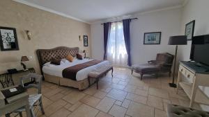 a bedroom with a bed and a chair and a television at Château de Floure - SPA et piscine extérieure chauffée in Carcassonne