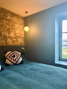 a bedroom with a blue bed and a stone wall at Entre Pierres et Rivière - 2 Gites avec wellness privatifs in Hotton