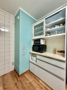 a kitchen with white cabinets and a microwave at Takumisou1 in Kiso