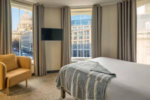 a hotel room with a bed and a chair and a window at COVE Cannon Street in London