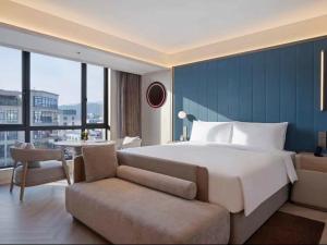 a bedroom with a large bed and a couch and a table at Orange Crystal Hotel Ningbo Ninghai in Ninghai