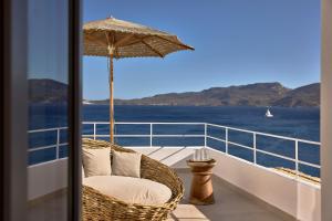 a wicker chair sitting on a balcony with an umbrella at Villa Soleil - Delmar Collection in Adamantas