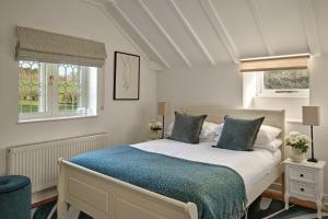 a bedroom with a bed with a blue blanket and two windows at The Gatehouse at Pudleston Court in Hatfield +20 photos