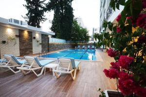 a swimming pool with chaise lounge chairs next to a building at Othello Hotel in Mersin