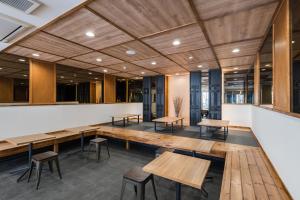 eine Cafeteria mit Holztischen und Hockern in der Unterkunft OKINI - Doyanen Hotels in Osaka
