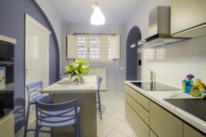 a kitchen with blue chairs and a table with a vase of flowers at Dimora il Respiro di Pisa in Pisa