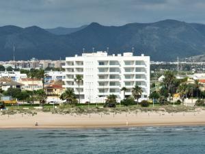 a large white building on a beach next to the ocean at Almar Suites Daimús in Daimuz