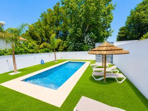 a swimming pool with chairs and an umbrella at Playa Fuente del Gallo I in Conil de la Frontera