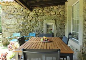 a wooden table with a bowl of fruit on a patio at Casa Moinho da Levada - Refúgio à beira do rio Coura in Paredes de Coura