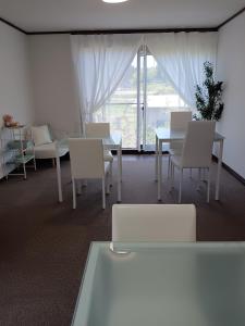 a room with white chairs and tables and a window at guest house mami in Taketa