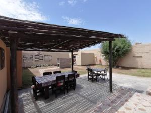 eine hölzerne Pergola mit Tischen und Stühlen auf einer Terrasse in der Unterkunft Skippers Backpackers CC in Walvis Bay