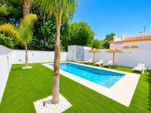 a backyard with a swimming pool and palm trees at Playa Fuente del Gallo I in Conil de la Frontera