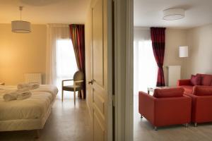 a bedroom with a bed and a couch and a chair at DOMITYS – Le Carroussel in Cabourg