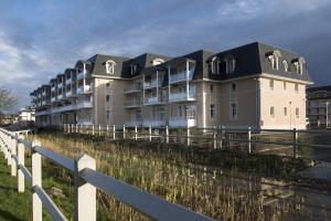 a row of apartment buildings next to a fence at DOMITYS – Le Carroussel in Cabourg
