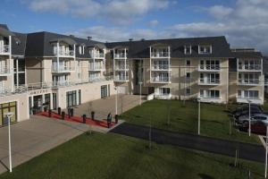 a large apartment building with a lawn in front of it at DOMITYS – Le Carroussel in Cabourg