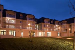 an exterior view of a large apartment building at night at DOMITYS – Le Carroussel in Cabourg