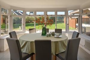 a dining room with a table and chairs and windows at Ponds View at Pudleston Court in Docklow