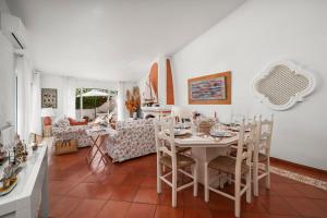 a white dining room with a table and chairs at Prainha Alvor - Cozy Villa in Alvor