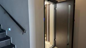 a bathroom with a glass shower door next to a staircase at Oniro Rooms & Suites in Leptokarya