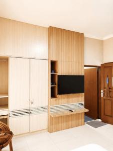 a living room with wooden cabinets and a flat screen tv at Enny's Guest House in Malang