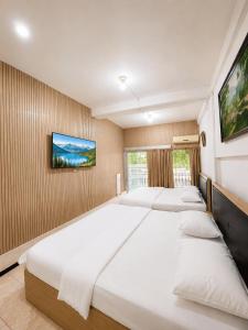 a bedroom with four beds and a tv on the wall at Enny's Guest House in Malang