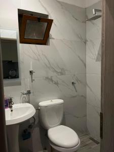 a white bathroom with a toilet and a sink at Vokopola Villa in Sarandë
