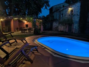 a swimming pool at night with two chairs and a table at Can Cirili Rustic Romantic apartment for couples or family events in Bordils