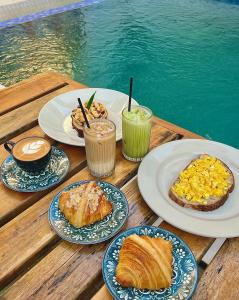 a wooden table with plates of food and drinks on it at NeNa Eat & Sleep Kuta in Kuta Lombok +18 photos