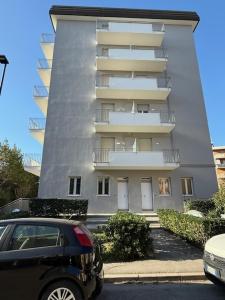 a car parked in front of a tall building at VIOLA CON SERVIZIO SPIAGGIA - LIDO ADRIANO in Lido Adriano