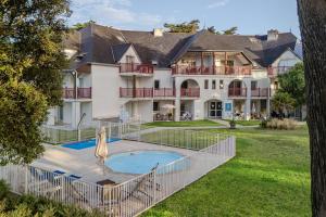 a large house with a swimming pool in the yard at Résidence Pierre & Vacances Premium Le Domaine de Cramphore in Le Pouliguen