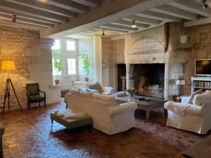 a living room with white furniture and a stone fireplace at Château de Bagneux in Bournan