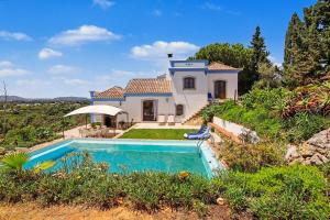 a villa with a swimming pool in front of a house at Casa Do Cerro in Luz de Tavira