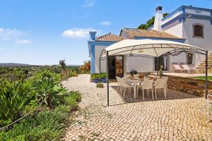a patio with a table and chairs under an umbrella at Casa Do Cerro in Luz de Tavira