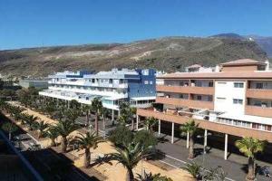 a group of buildings with palm trees and a mountain at Casas Galloway - Puertito Güímar. Sol y comodidad. in Puertito de Güímar
