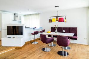a living room with a dining room table and purple chairs at baadhaus - 4 Sterne Superior in Traunkirchen