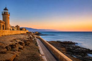 a lighthouse on the shore of the ocean at sunset at Kampaoh Roquetas in Roquetas de Mar +35 photos