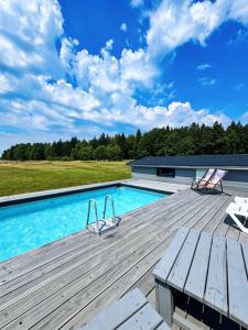 a swimming pool with two chairs on a wooden deck at Izerska Baza - basen, ebike, narty, sauna, jacuzzi, las blisko Świeradów Zdrój in Giebułtów
