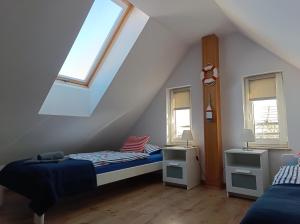 a attic bedroom with two beds and two windows at Baltic Sea in Jastarnia