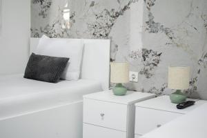 a bedroom with a white bed and two tables with lamps at Motel Nova in Strumica