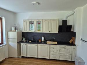 a kitchen with white cabinets and a white refrigerator at Elly Apartment - 20 min to Ljubljana in Kresnice