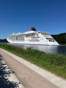 a cruise ship on the water next to a sidewalk at Apartment in Fockbek