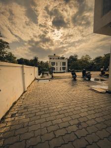 a brick courtyard with a white building in the background at TGC Resort And Hotel Arpora in Calangute