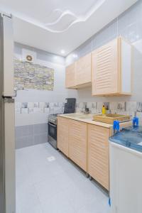 a kitchen with wooden cabinets and white tile walls at شقه الاطلال in Jeddah