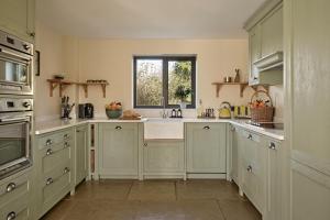 a large kitchen with white cabinets and a window at Meadow View House at Pudleston Court in Docklow