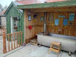 a wooden building with a bath tub in it at West Stable Cottage in Cameron