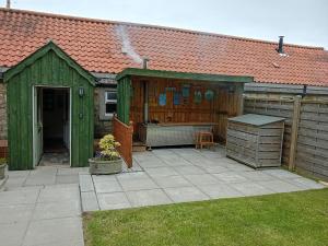 a green shed with a grill in a yard at West Stable Cottage in Cameron