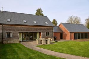 a house with a patio and some chairs in the yard at Meadow View House at Pudleston Court in Docklow