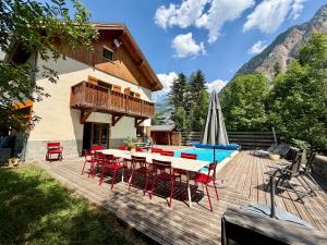 a wooden deck with a table and chairs and a pool at Chalet Les Ecrins in Vénosc